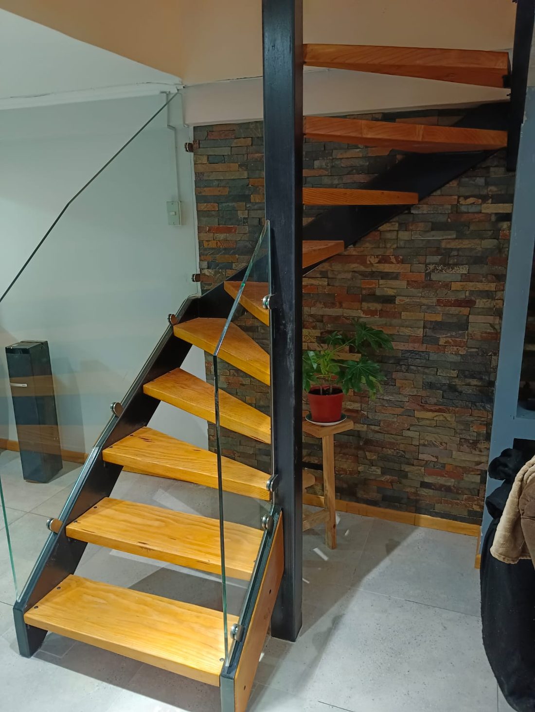Escalera metálica con peldaños de madera y baranda de cristal